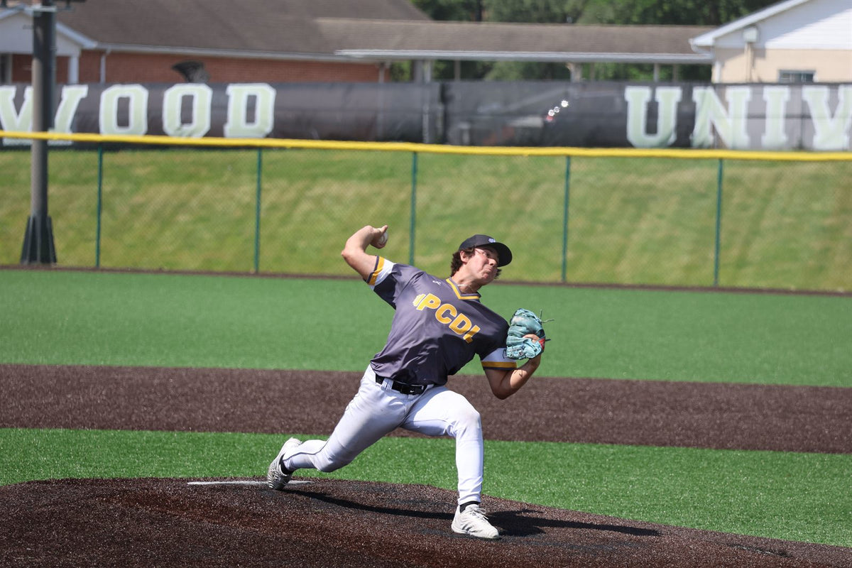 PCDL pitcher delivering a pitch in front of the Lindenwood University outfield wall